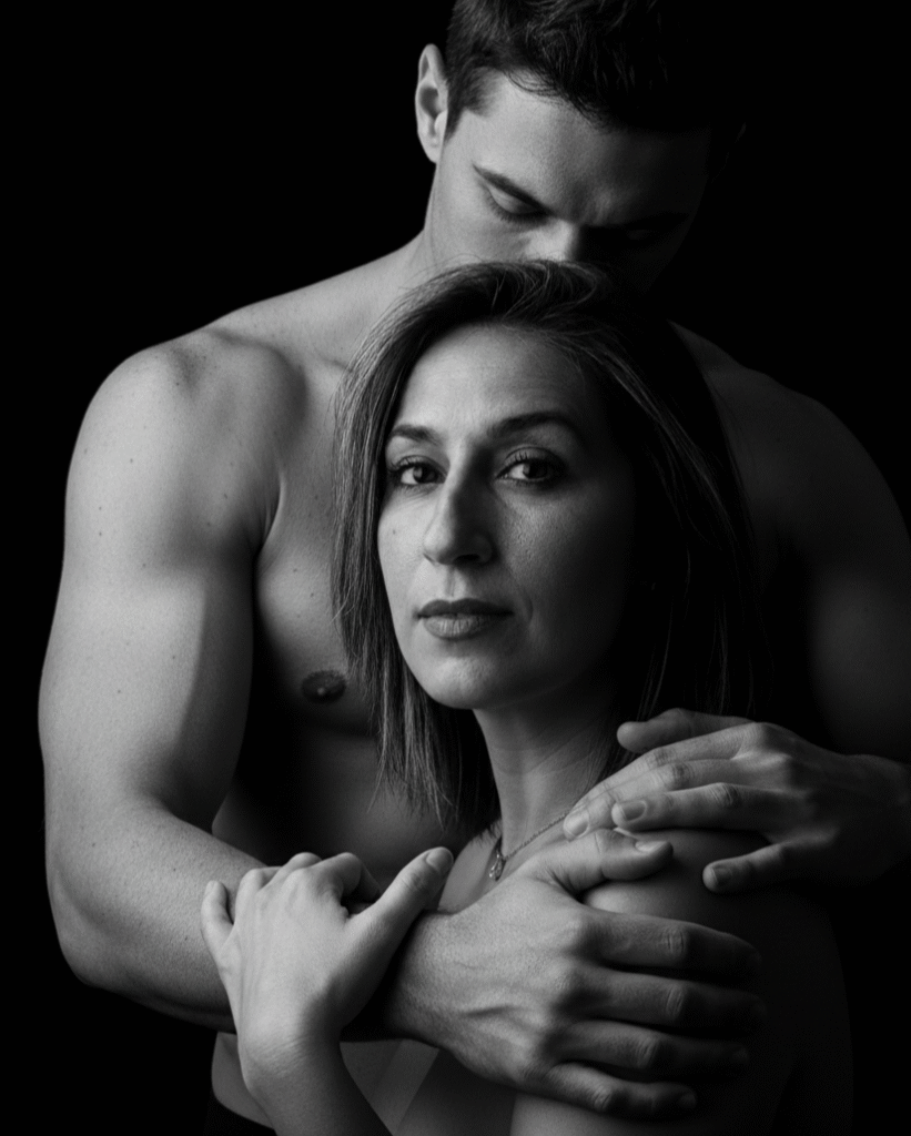 Homem abraçando uma mulher por trás, em um retrato em preto e branco, transmitindo intimidade e vulnerabilidade.